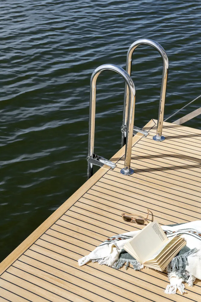 Close up deck details on a houseboat built by Mason Marine Industries, hsowing a towel, book and sunglasses